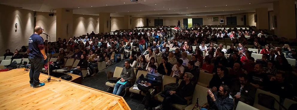 Diego Serrano hablando desde el escenario ante un auditorio lleno de público